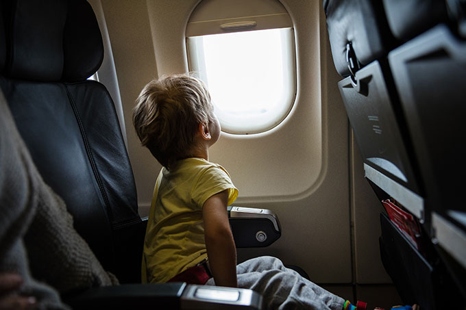 Autorização para menor viajar: imagem de uma criança sentada na poltrona do avião olhando para a janela